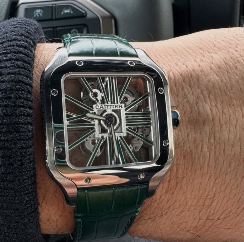 Close-up of a Cartier square watch with a green crocodile strap on a wrist.