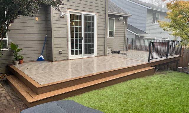 There is a deck in the backyard of a house with sliding glass doors.