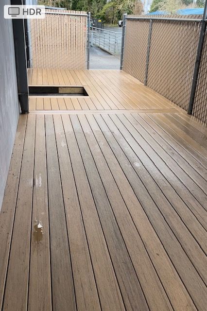 A wooden deck with a chain link fence in the background.