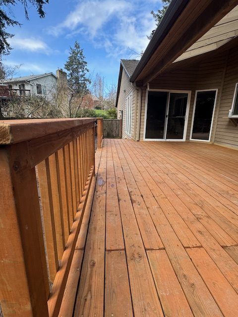 A large wooden deck with a railing and sliding glass doors
