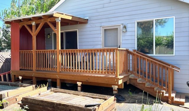 A white house with a wooden deck and stairs.