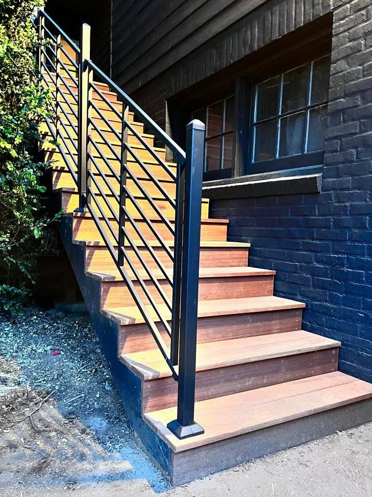 A set of stairs leading up to a brick building with a black railing.