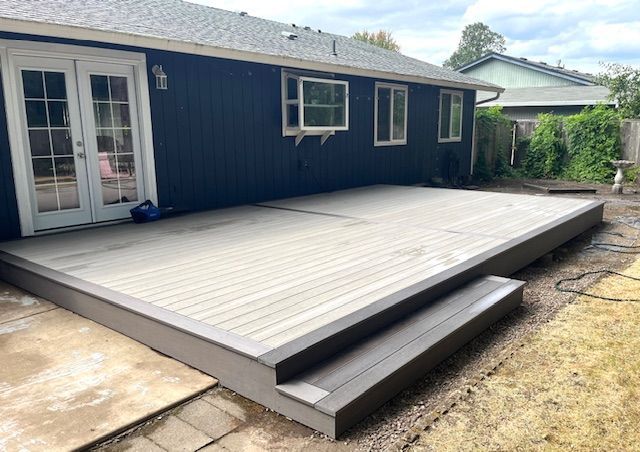 A blue house with a large deck in front of it.