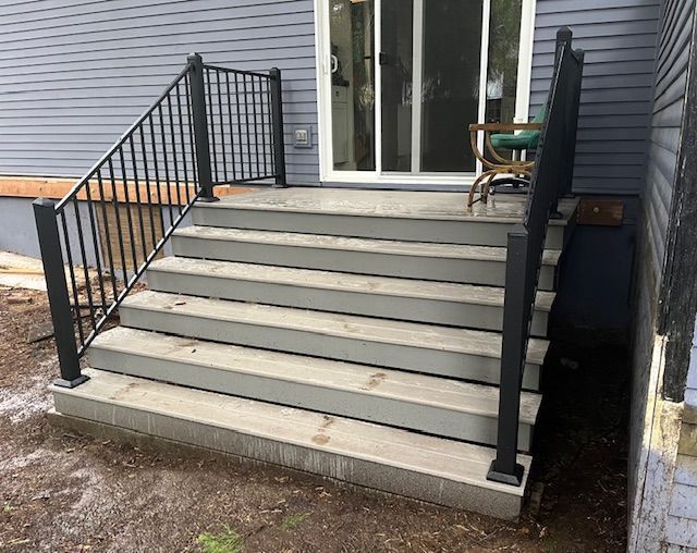 A set of stairs leading up to a patio with a black railing.