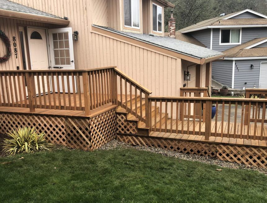 A wooden deck with stairs leading up to it is in front of a house.