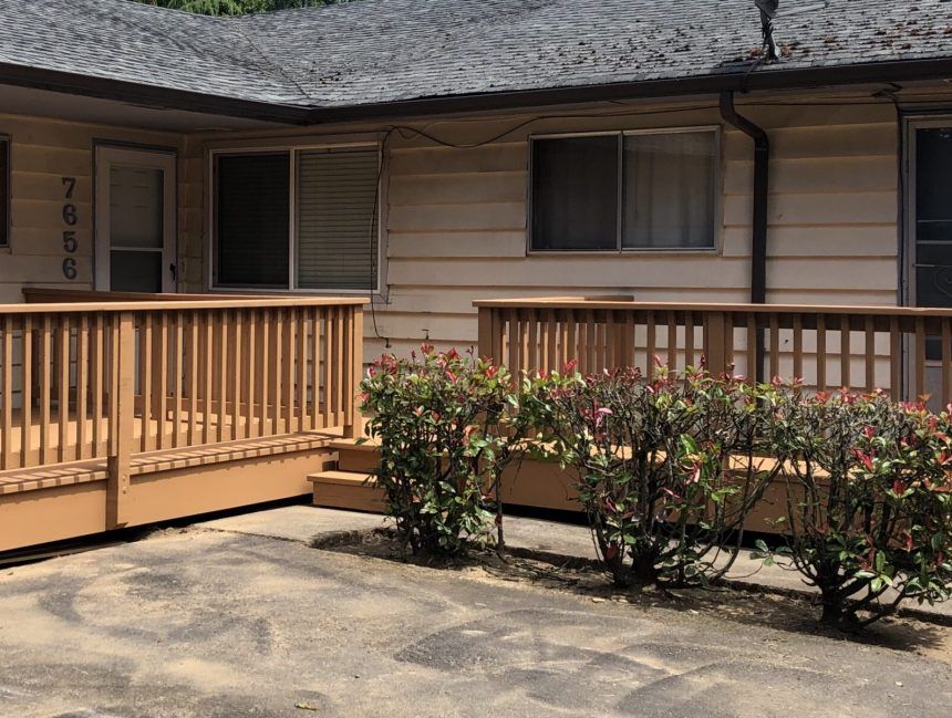 The front of a house with a wooden deck and stairs