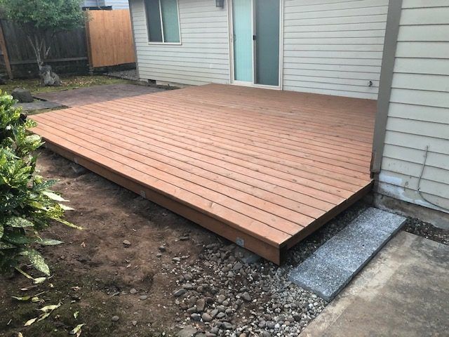 A wooden deck is in the backyard of a house.