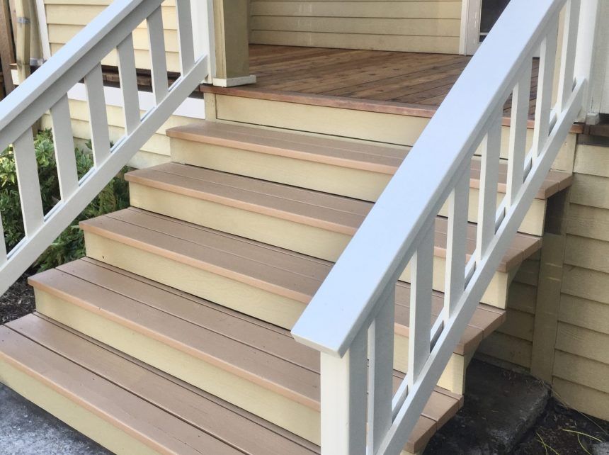 A set of wooden stairs with a white railing