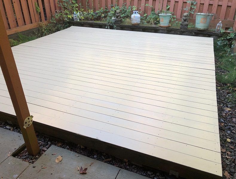 A white wooden deck with a wooden fence in the background.
