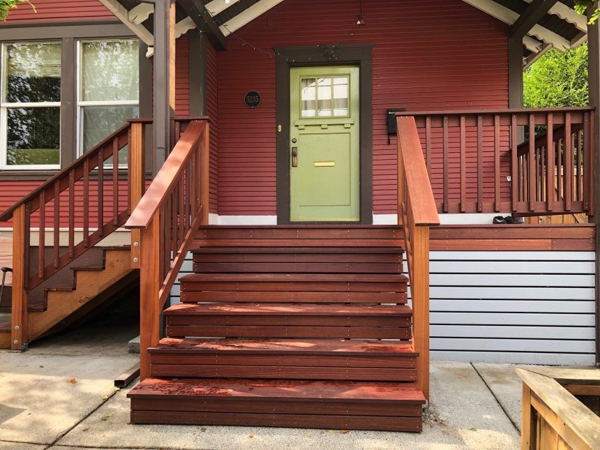 A red house with a green door and stairs