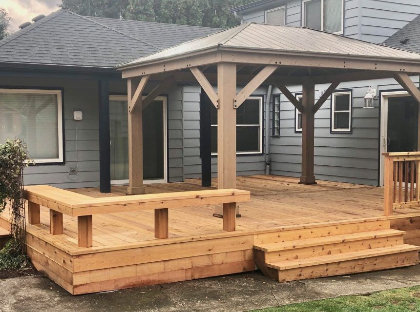 A wooden deck with a gazebo in the backyard of a house