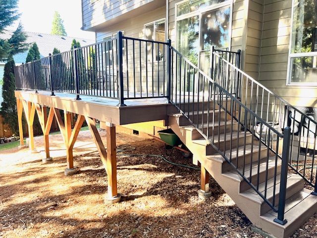 A deck with stairs leading up to it and a metal railing.