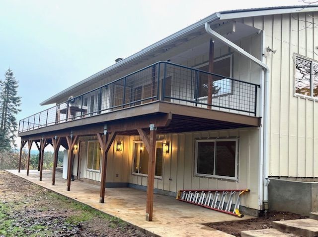 A house with a large deck and a ladder in front of it.