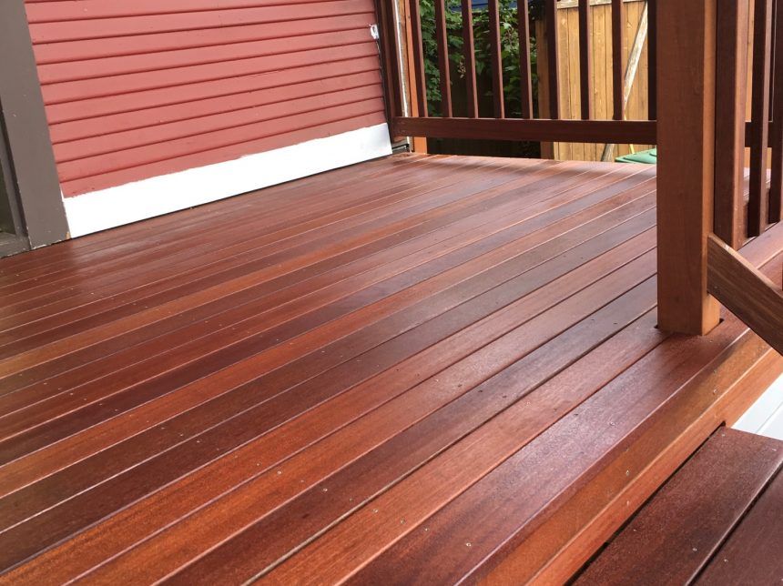 A wooden deck with a red house in the background