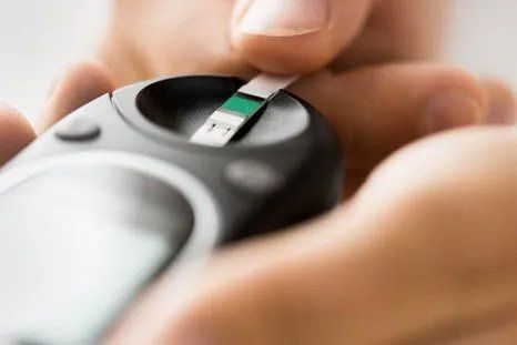 A person is taking a blood sugar test with a glucose meter.
