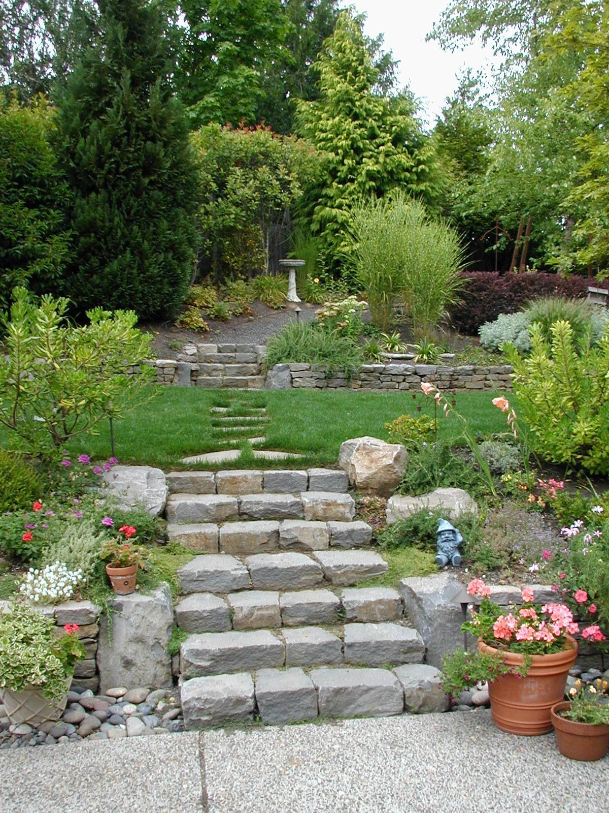 Stone garden steps leading to a lush terraced yard with greenery and potted flowers