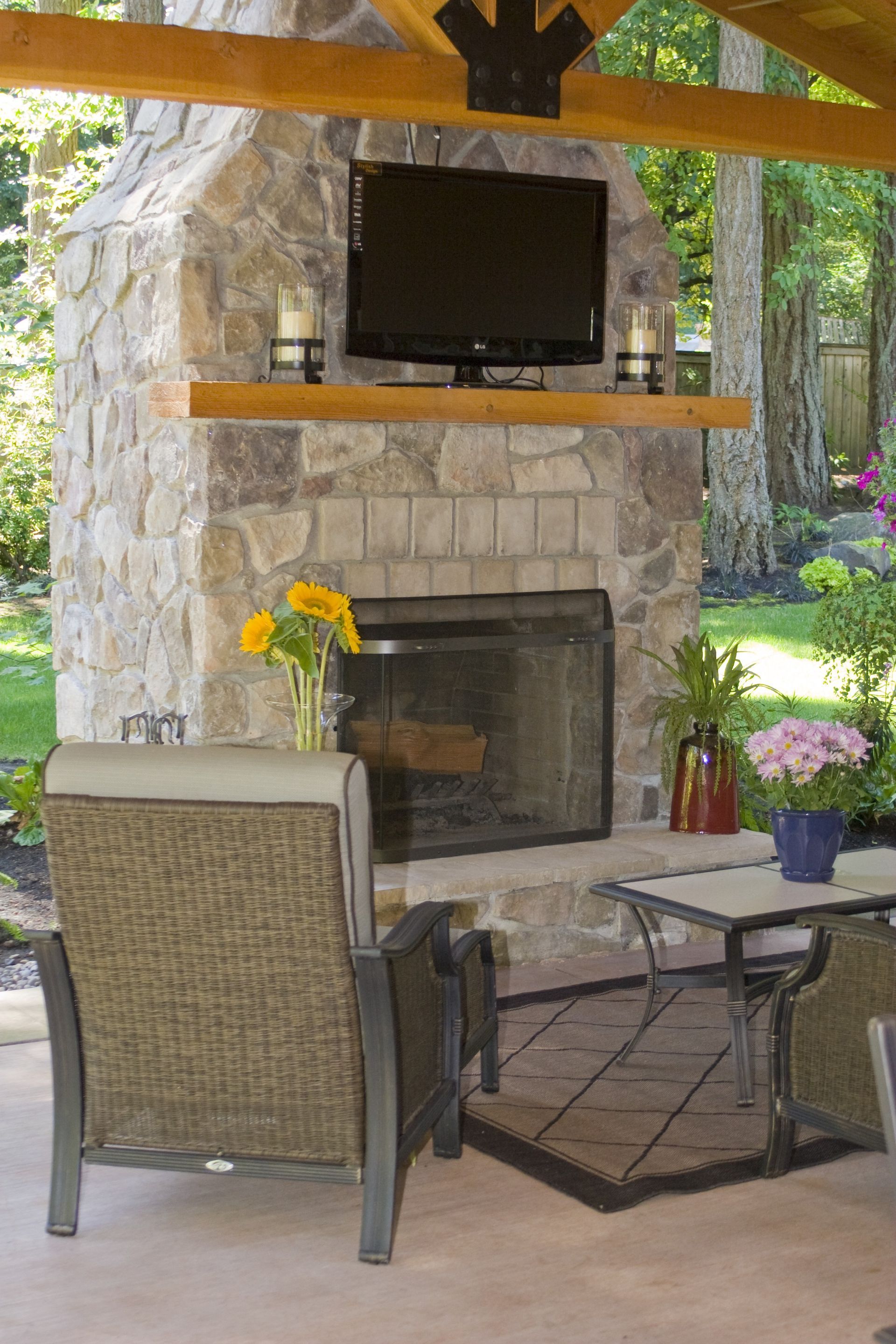 Patio fireplace with TV, woven chair, and small table in an outdoor seating area