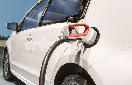 A white electric car is plugged into a charging station