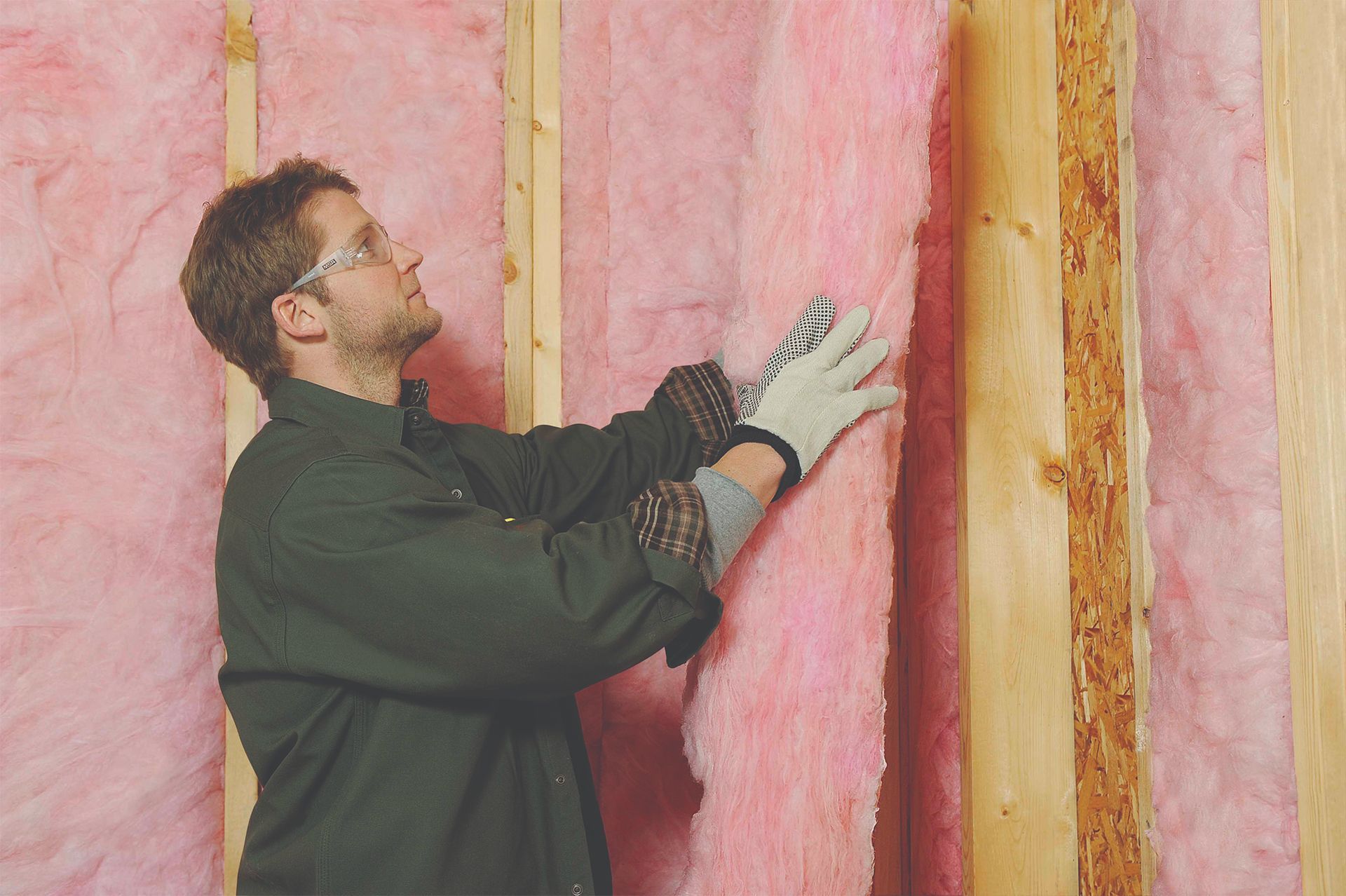 a man is installing pink insulation on a wall