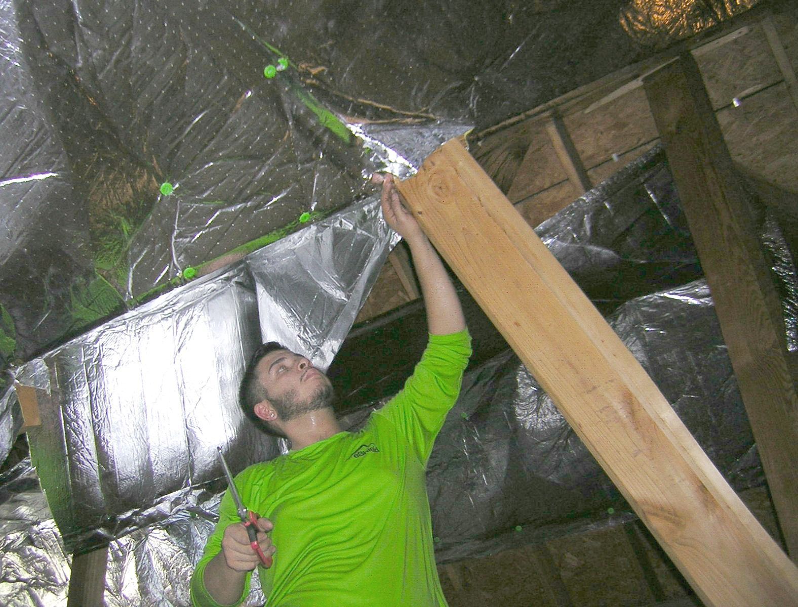 a man in a green shirt is working in an attic