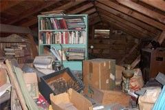 a cluttered attic with a bookshelf filled with books and boxes