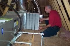 a man is kneeling down in an attic working on an air conditioner