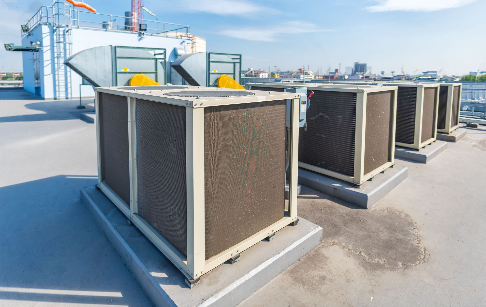 Row of rooftop HVAC units on a flat roof under a clear sky