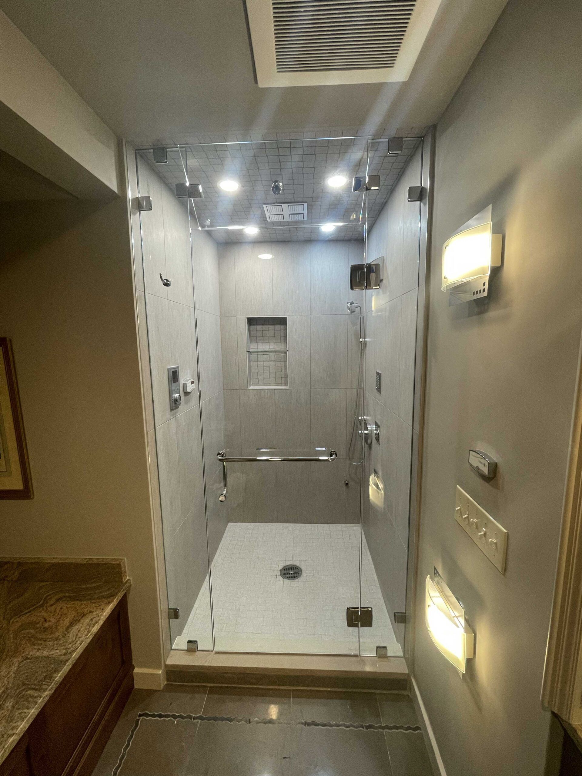 A bathroom with a walk in shower with a glass door