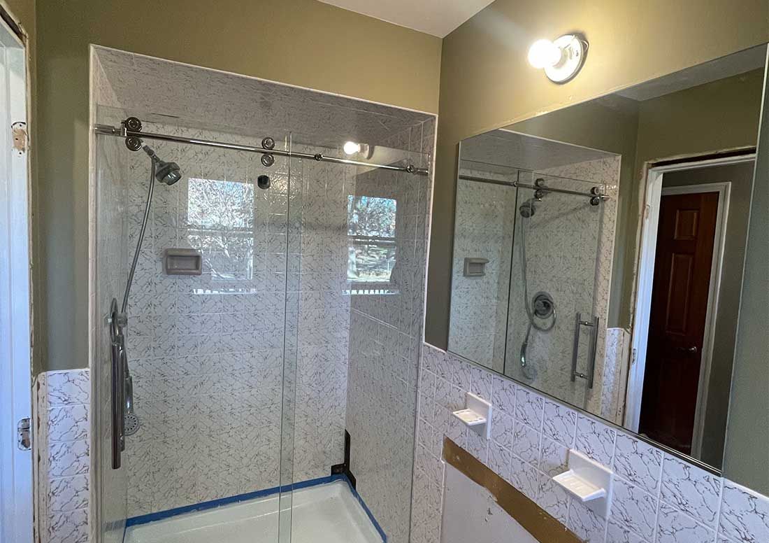 A bathroom with a walk in shower and a large mirror.