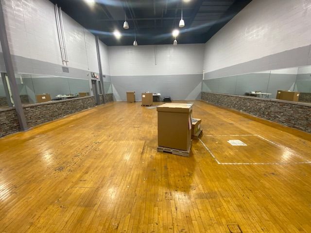 A large empty room with wooden floors and mirrors.