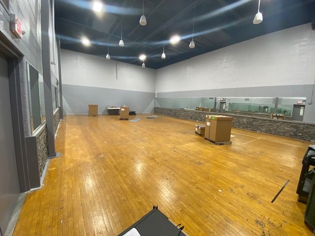 A large empty room with a wooden floor and a mirror.