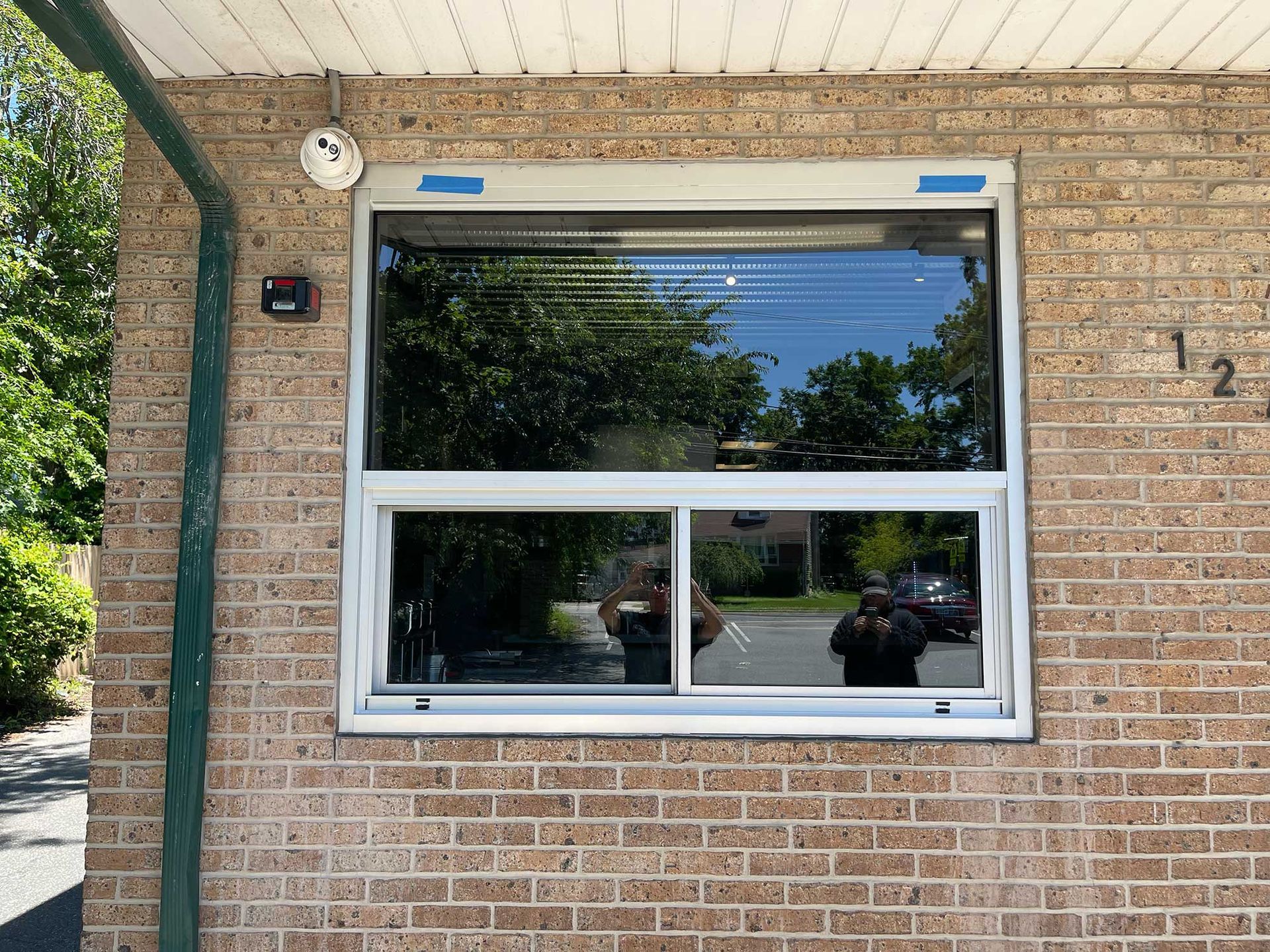 A person is taking a picture of a window on a brick building.