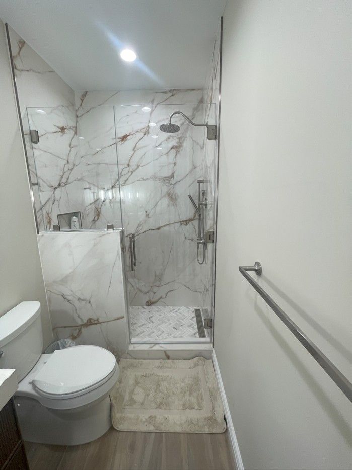 A bathroom with a toilet , sink and shower.