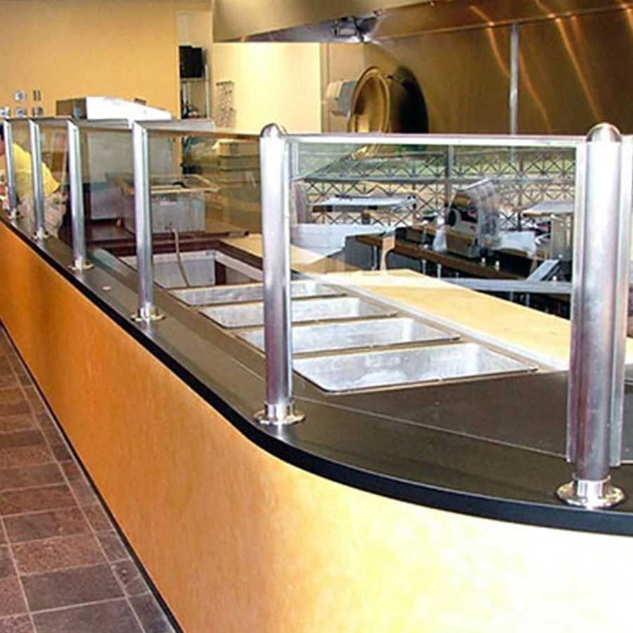 A long counter in a restaurant with a stainless steel railing