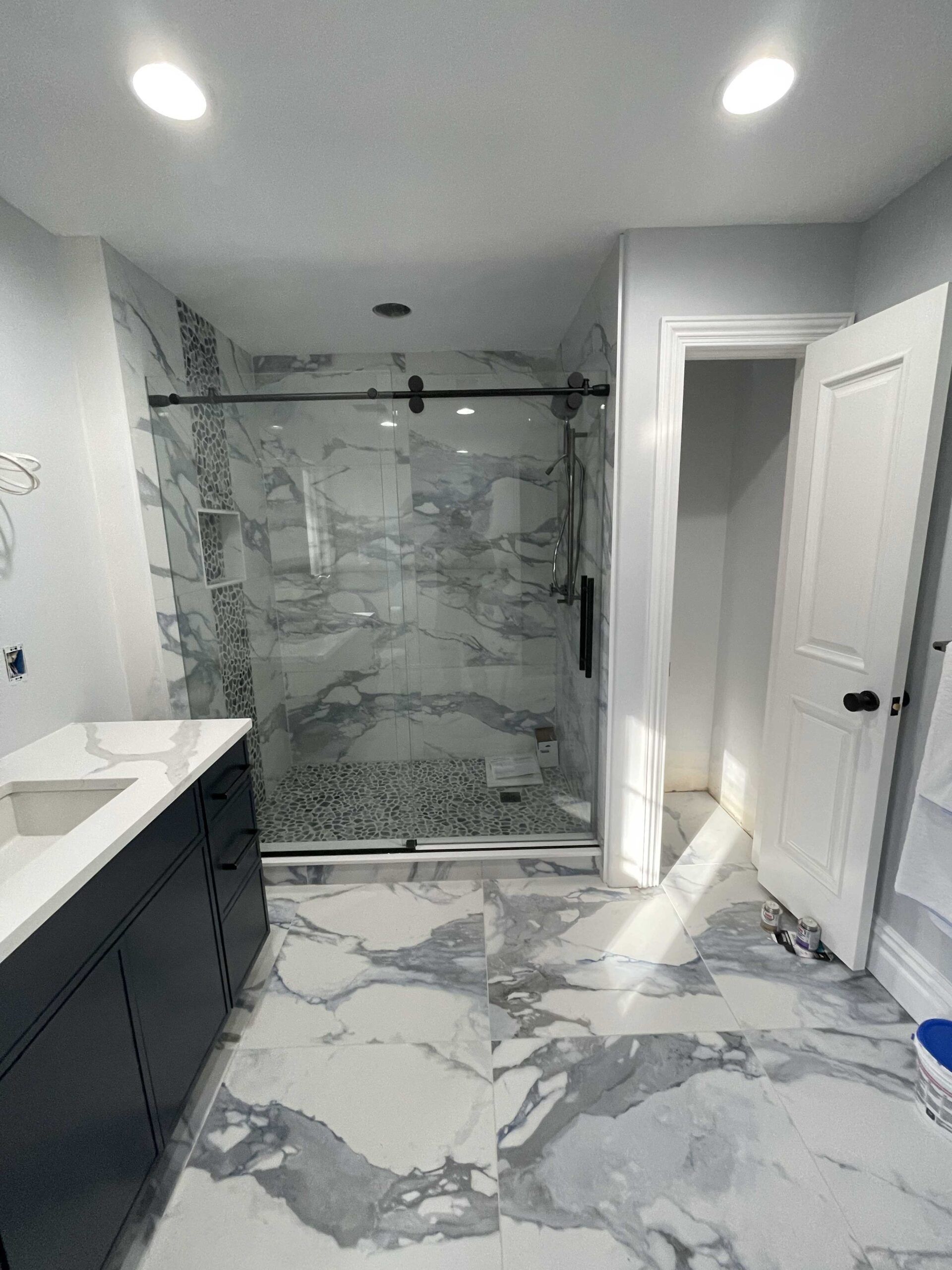 A bathroom with marble floors and a walk in shower.