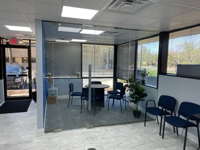 A waiting room with a glass wall and a table and chairs