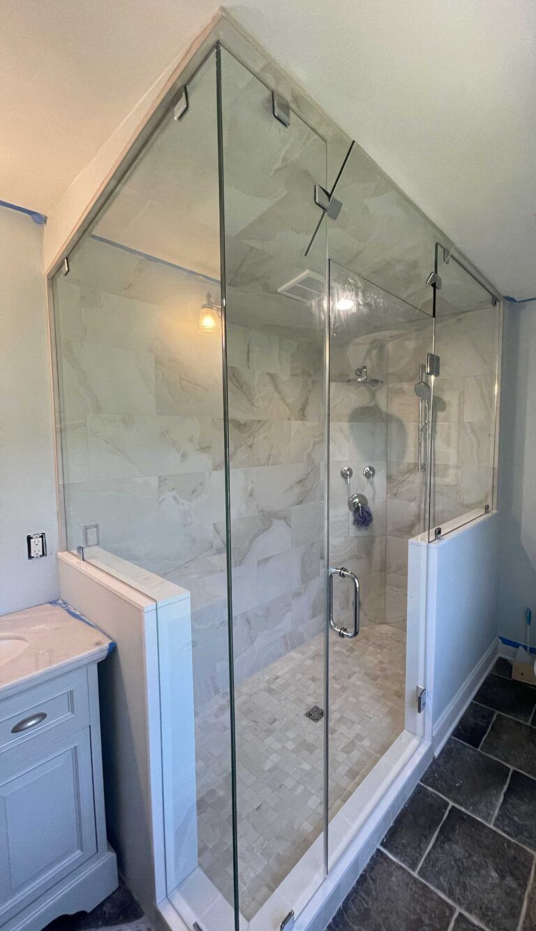 A bathroom with a walk in shower with a glass door.