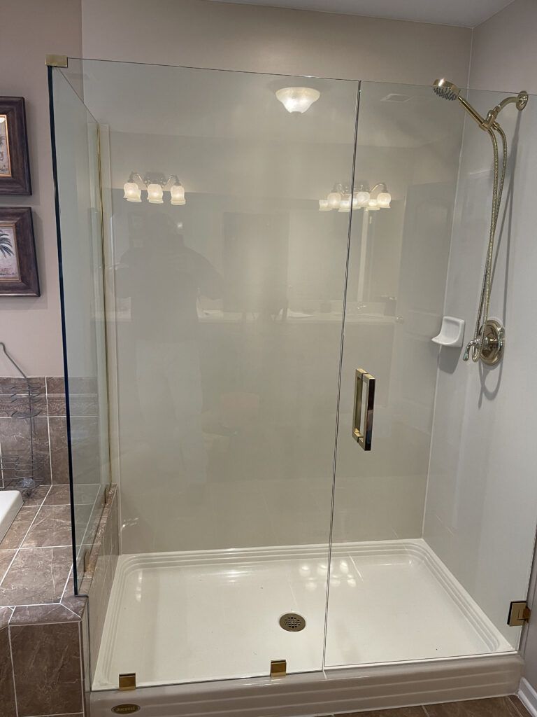 A bathroom with a walk in shower with a glass door and a shower head.