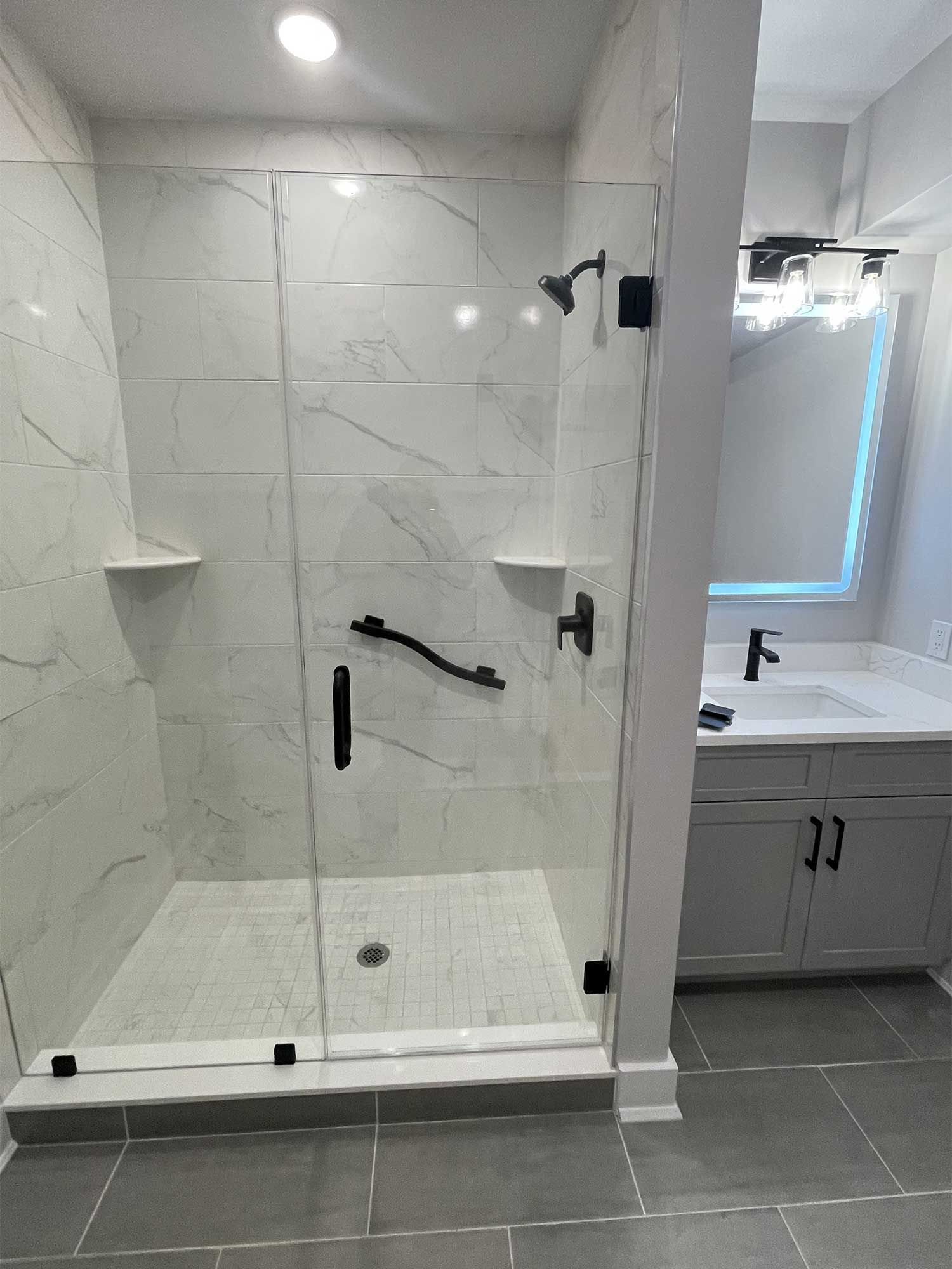 A bathroom with a walk in shower and a sink.