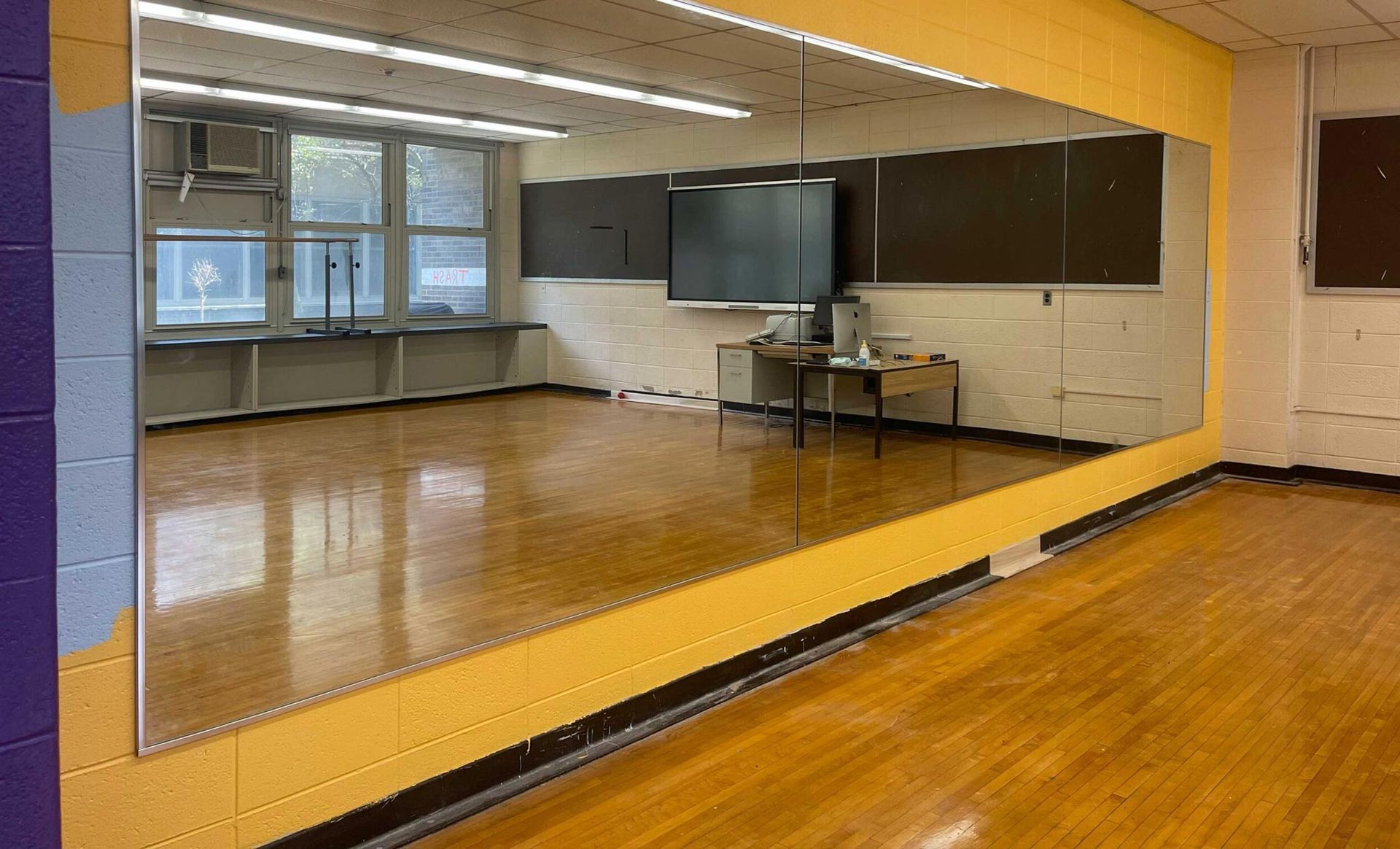 A large dance studio with a large mirror on the wall.
