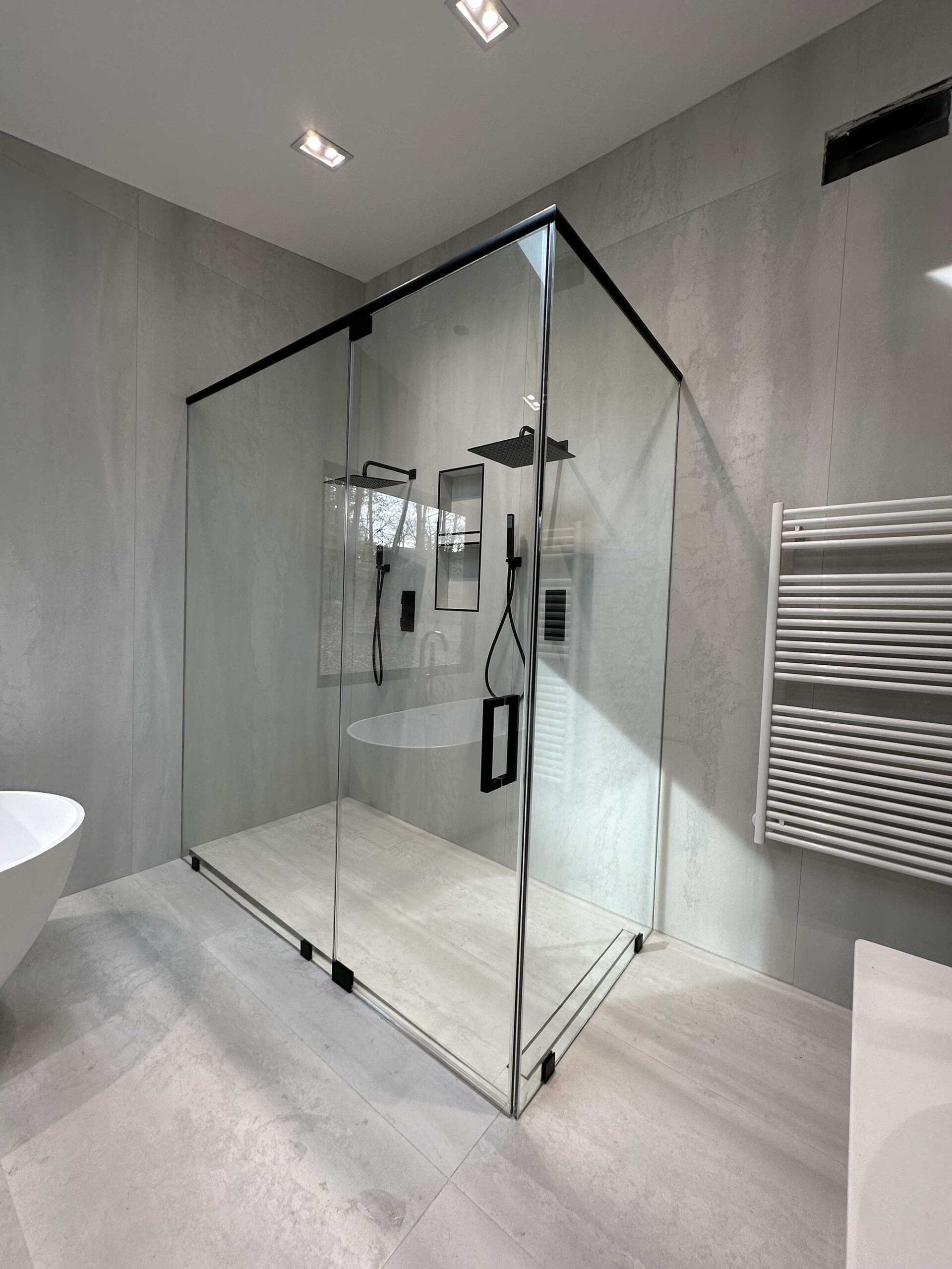 Modern bathroom with glass shower, toilet, floating sink, and lit mirror.