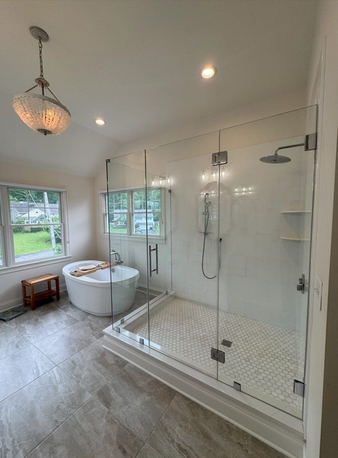 Modern bathroom with a glass shower, a tub, and tiled floors.