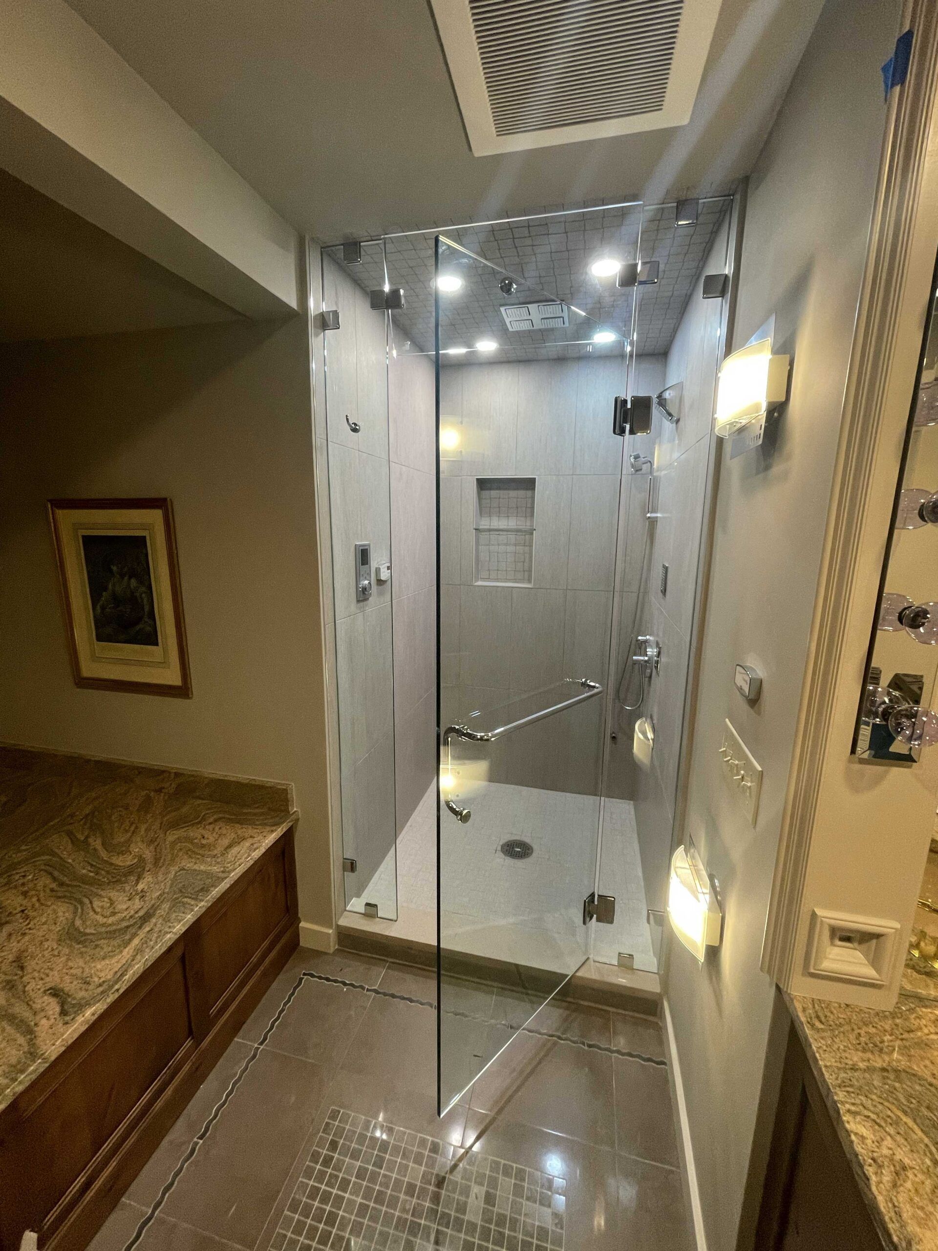 A modern bathroom with a glass-enclosed shower, neutral-colored walls, and granite countertops.