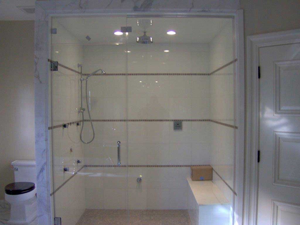Glass shower enclosure with white tile walls and a built-in bench.