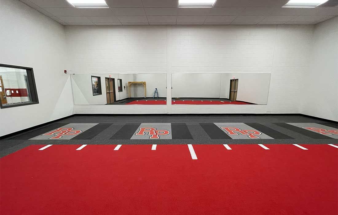 A large room with a red carpet and mirrors on the wall.