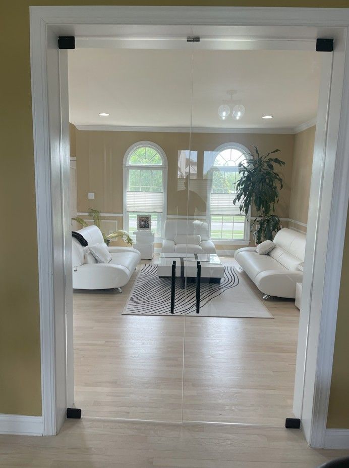 A living room with white furniture and a glass door.