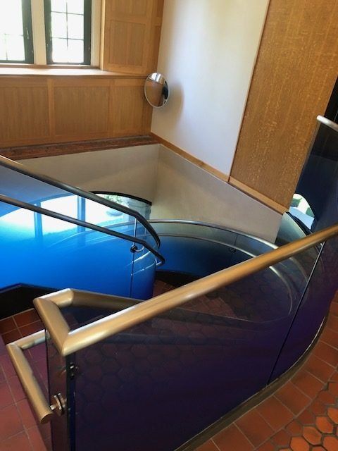 A blue staircase with a glass railing in a building