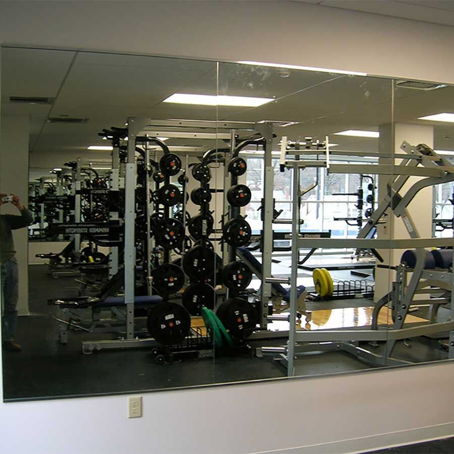 A man is taking a picture of a gym with a large mirror