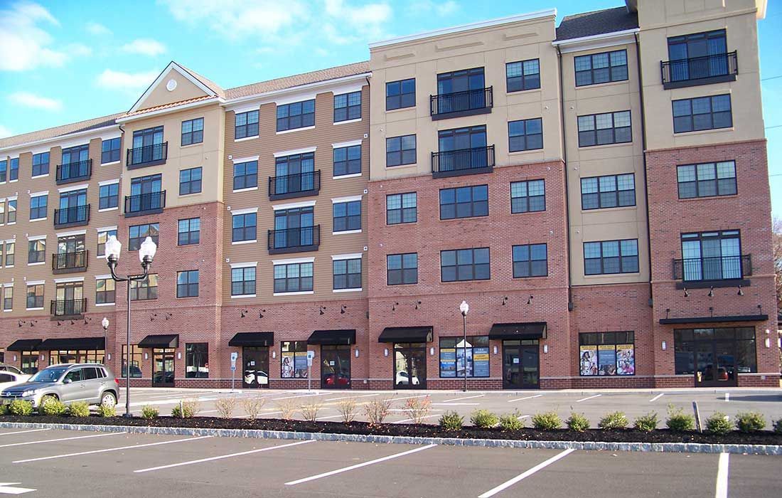 A large brick building with a lot of windows and a parking lot in front of it