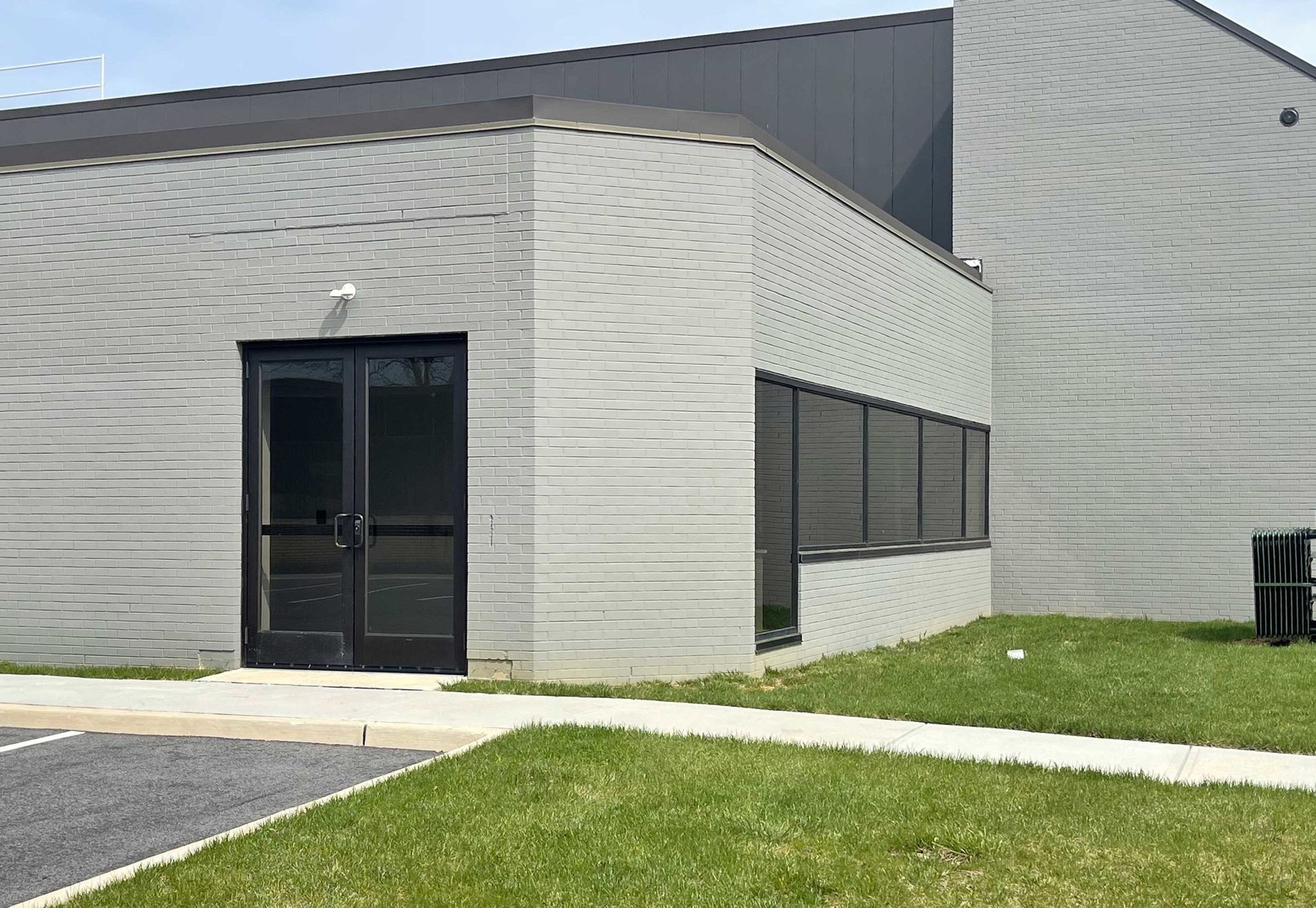 A large gray brick building with a black door and windows.